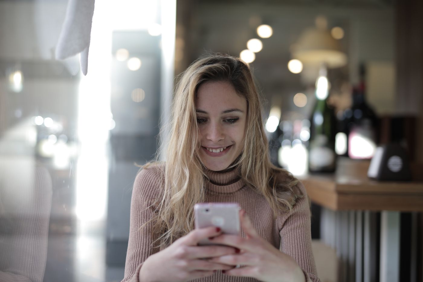 Mujer comprando en línea desde su teléfono en una cafetería